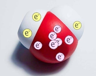 Model of a water molecule with 2 electrons displayed on one hydrogen atom, 1 electron displayed on the other hydrogen, and 7 electrons on the oxygen atom.